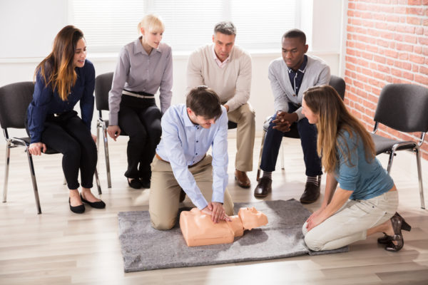 First Aid Instructor Showing CPR Training On Dummy